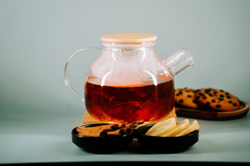 Warm tea served with cookies and spices on a light background