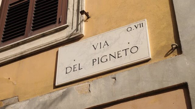 The street sign &ldquo;Via del Pigneto&rdquo; mounted on an old wall marked by graffiti, reflecting urban identity and cultural resistance.