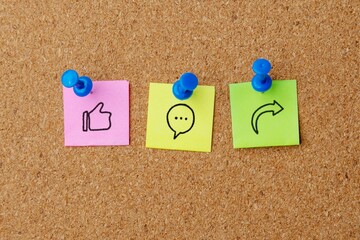Obraz premium Notes pinned to a corkboard display social media icons for Like, Comment, and Share. Social media marketing, engagement, feedback, and online interaction concept.