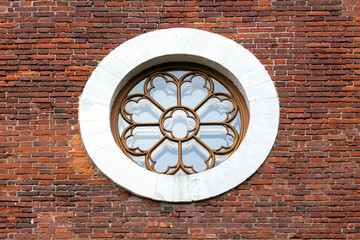 A decorative circular window with intricate frame sits in a white stone circle