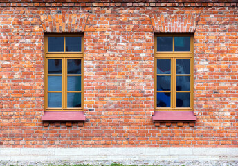 Two windows with wooden frames set in a rustic red brick wall. Photo texture
