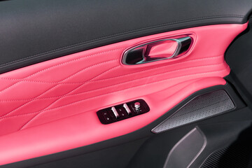 Driver-side car door with vibrant pink leather, metallic handle, control panel and speaker grille