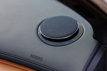 Close-up of luxury car dashboard featuring circular speaker with metallic trim