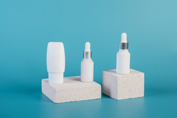 Cosmetic product in tube, bottle, lotion or serum with stylish props on blue background. 