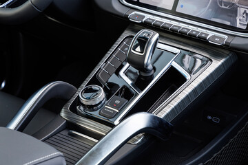 Modern car center console with metallic gear shifter, rotary dial, USB ports and drive mode buttons