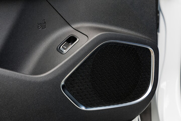 Modern car door panel featuring geometric speaker grille, metallic trim and bottle holder icon