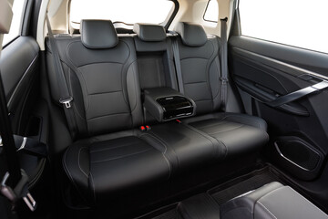 Modern car back seat with black leather upholstery, fold-down armrest and cup holders