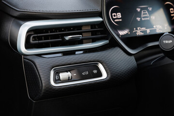 Close-up of car dashboard left of steering wheel, featuring headlight knob, TRIP button and digital cluster