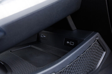 Modern car center console with dual USB ports, wireless charging pad and netted storage pocket