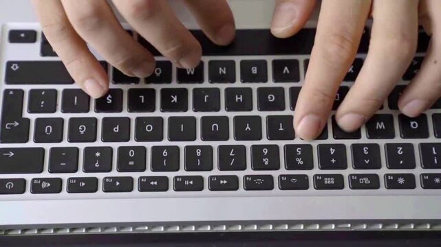 Close-up fingers typing on laptop keys, crisp keystroke rhythm