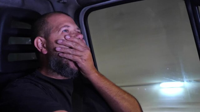 tired truck driver yawning repeatedly while driving through a tunnel at night, revealing exhaustion and the danger of fatigue behind the wheel.
