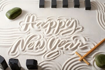 Naklejka premium Happy new year written in sand with stones and brush