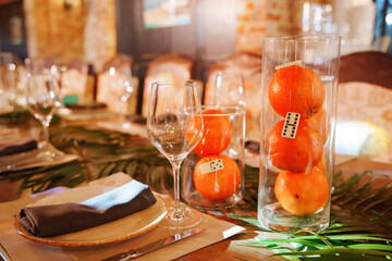 Colorful table setting with oranges and glasses in a warm dining space