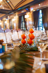 Elegant table setting with decorative glass vases and fresh fruit in restaurant
