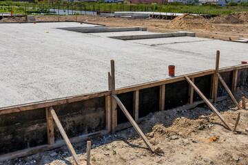 Workers pour cement to create a solid foundation slab for a new house in a residential development...