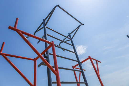 A horizontal training bar structured for fitness activities stands under a clear blue sky in a park, inviting athletes to engage in outdoor workouts