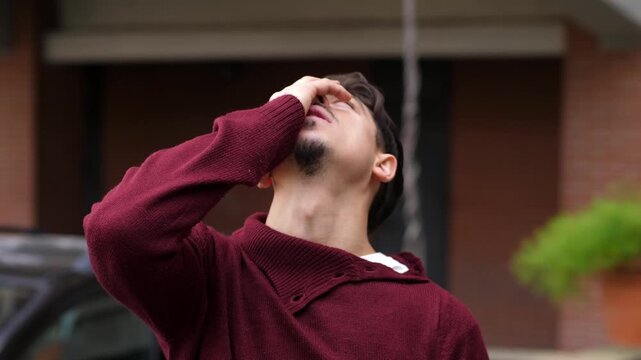A young man with dark hair in a sweater sits showing despair and frustration because he forgot something, expressing human vulnerability indoors.