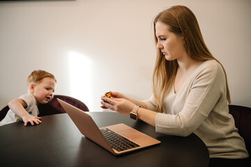Mother working from home with kid. Quarantine and closed nursery school. Distance learning through war. Child make noise and disturb woman work. Homeschooling and freelance job. Stay at home.