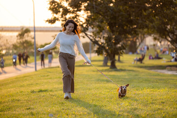 Woman walking with her dachshund dog at park in the evening