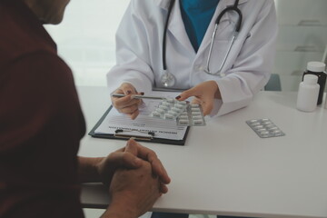 Doctor prescribing medicine giving pills to senior grandmother patient at hospital.