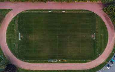 Soccer field surrounded by athletics track, in Baasrode, Belgium - Top down aerial view