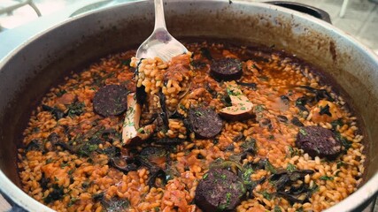 Traditional Spanish paella dish with chicken and vegetables, mushrooms, sausages at restaurant. High quality 4k footage