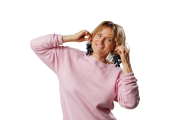 Smiling woman in a pink sweatshirt playfully holds bunches of grapes like earrings, isolated on white background. Fun, quirky concept perfect for healthy or humorous themes