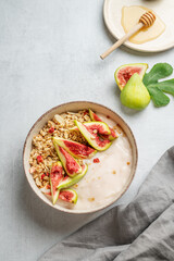 Natural yogurt with granola, figs and honey in a bowl on a light background
