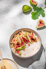 Natural yogurt with muesli, figs and honey in a bowl on a marble background