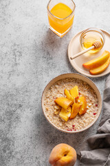Oatmeal with peaches and nuts  in a bowl on a gray background with honey,