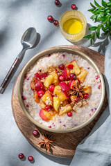 Overnight oatmeal with apples, cranberries, and cinnamon in a bowl on a wooden board
