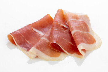 Thin slices of prosciutto ham on white background