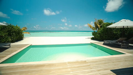 A private plunge pool on a wooden deck opening directly onto a white-sand beach and the vast turquoise ocean under a bright sky