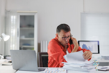 Overwhelmed man talking on phone with documents
