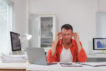 Mature businessman suffering headache at busy office desk