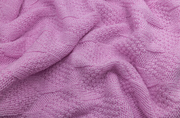 Pink fabric texture. Pink knitted wool texture. Wool knit fabric. Knitted background. Crinkled wool knit texture. Pink knitted background. The fabric is knitted from wool yarn. 