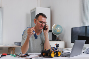 Man developing robotics project receiving phone call