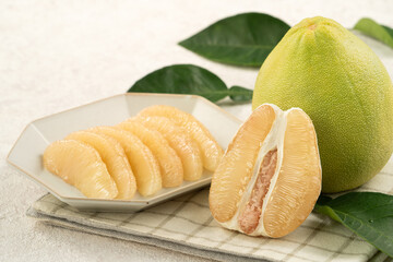 Fresh pomelo fruit with leaf on white table background.