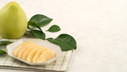 Fresh pomelo fruit with leaf on white table background.
