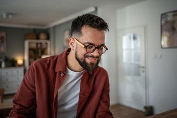 Young man with beard smiling in glasses at home