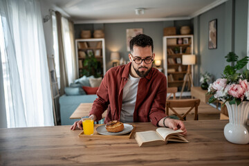 Man reading book at breakfast, enjoying relaxed home lifestyle