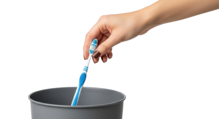 Isolated hand throws toothbrush into gray trash bin for disposal after oral care routine