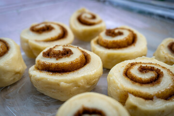 Homemade Cinnamon Rolls Ready to Bake. An appetizing close-up of raw, unbaked sweet pastry swirled with cinnamon sugar. Shallow depth of field highlights the texture of this delicious comfort food.