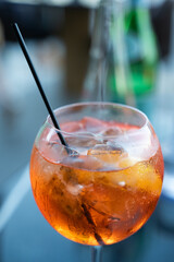 A refreshing glass of orange liquid complete with ice and a black straw