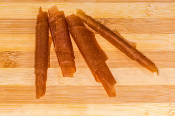 Twisted apricot pastila rolled into tubes on a cutting board