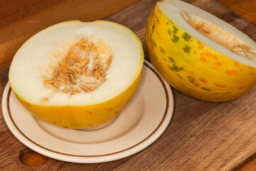 Halved yellow melon on dish on cutting board close-up