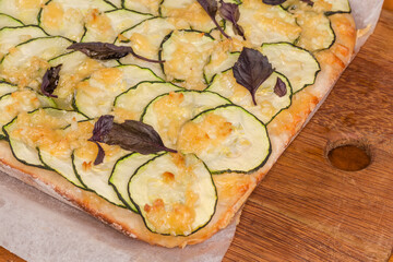 Cooked zucchini pizza on cutting board, fragment close-up