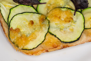 Part of zucchini pizza on white plate close-up