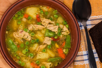 Vegetable soup serving with meat in clay bowl, top view