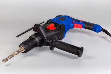 Electric rotary hammer with inserted metal drill on gray background